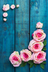 Wedding border with pink rose flowers on blue wooden background