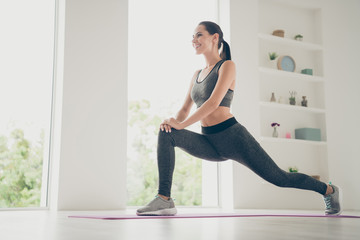 Low below angle view photo of cheerful positive nice cute pretty girlfriend stretching showing power of beauty her legs twine smiling toothily indoors on carpet