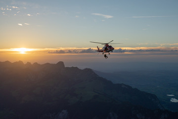 Fototapeta na wymiar Hubschrauber, der über Landschaft gegen den Himmel in den Sonnenuntergang fliegt