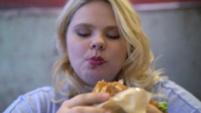 Fat woman eating greasy burger and french fries, addiction to fast food, obesity