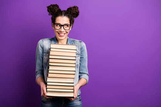 Photo of funny student lady holding many books carry literature home tricky looking on librarian wear specs casual denim outfit isolated purple color background
