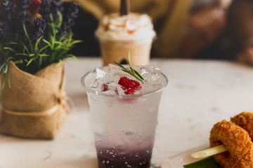 Refreshing red translucent drinks with ice and raspberries.