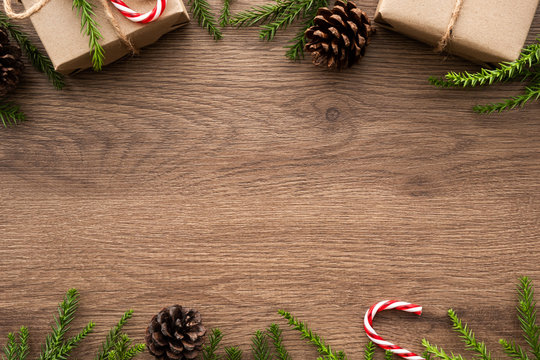 Wood table with Christmas decoration including gift boxes, candy cane, pine branches and pine cones. Merry Christmas and happy new year concept. Top view with copy space, flat lay.
