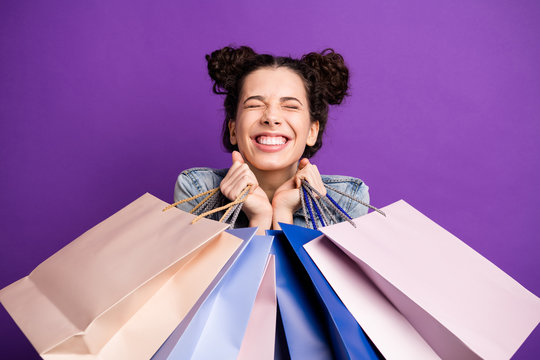 Close up photo of cheerful excited girl go shopping hold many bags feel dream dreamy enjoy her purchases wear denim jeans jacket outfit isolated over violet color background