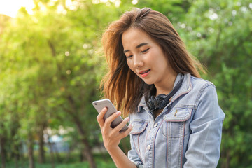 Young Asian woman using a smart phone outdoor. Lifestyle and technology concept.
