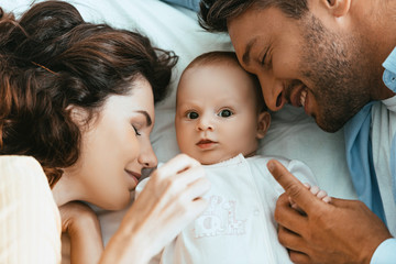 happy mother and father lying near adorable infant with closed eyes