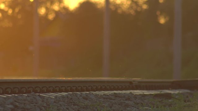 Motorcyclist or scooter, people, vehicle and pedestrians move through the railway level crossing on the Sunset. Dangerous electrified railroad section for train crash, catastrophe or accident