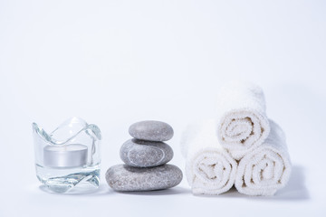 Soft towels, stones and candle for skin care and spa on a white background