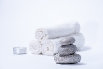 Obraz na płótnie Canvas Soft towels, stones and candle for skin care and spa on a white background