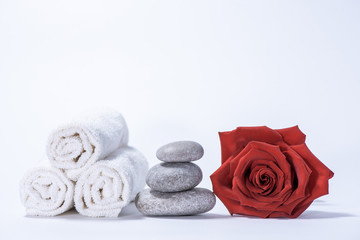 Fototapeta na wymiar Soft terry towels, rose and stones for skin care and spa on a white background