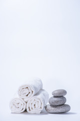 Obraz na płótnie Canvas Soft terry towels and stones for skin care and spa on a white background