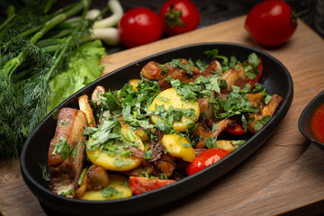 roast lamb in a black oval plate on a wooden board on a dark background