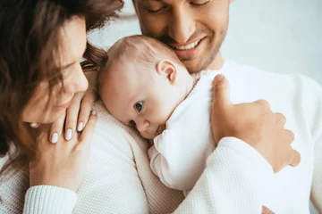 Foto op Plexiglas cropped view of happy man holding adorable baby near smiling wife © LIGHTFIELD STUDIOS