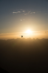 Helicopter Flying Over Mountains Against Sky During Sunset