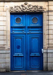 Typical design style of large antique blue wooden door on the streets of Paris France.