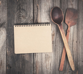 open empty notebook and two wooden spoons on a gray background