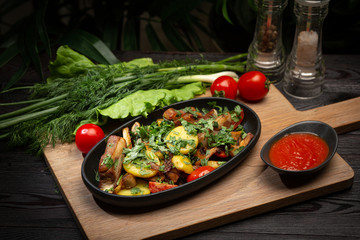 roast lamb in a black oval plate on a wooden board on a dark background