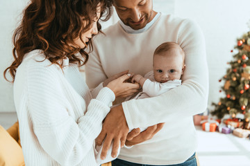 smiling woman touching hand of cute little daughter lying on fathers hands