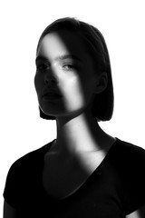 Fashionable beauty portrait. Black silhouette on white background. Girl with a spot of light on her face. 