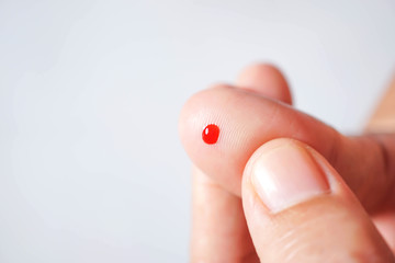 Small drop of red blood on finger..