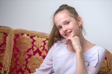 Naklejka premium Beautiful young girl sitting on the sofa by the fireplace