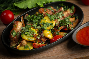 roast lamb in a black oval plate on a wooden board on a dark background