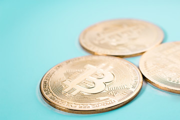 The close up of three gold Bitcoins in plain background.	