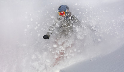 freerider in a bright suit rides snowboarding with large splashes of snow on a sunny day. Young...