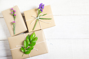Brown hand made gift box decorated with green leaf pink and purple froral on withe wooden background with copy space.Top view.