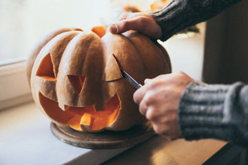 Man cutting pumpkin for Halloween party with a knife
