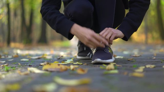 Woman tie shoes during autumn park run