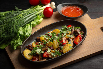 roast beef in a black oval plate on a wooden board on a dark background