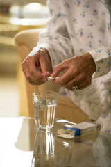 Close-up of a senior woman taking medicine with a glass of water