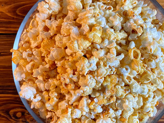 Popcorn in glass bowl on wooden background