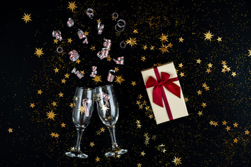 Obraz na płótnie Canvas In anticipation of the holiday. Glasses, gold sequins and candies on a black background.