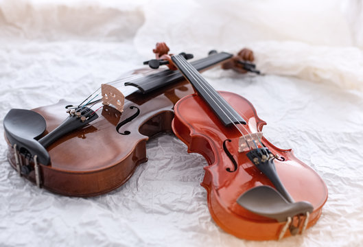 Two different size of violins put on grunge surface background,vintage and art tone,blurry light around