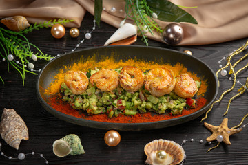 tartar shrimp with avocado and spices on a black oval plate