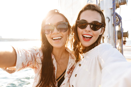 Women friends outdoors on yacht in sea take a selfie