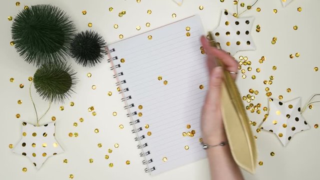 2020 New Year goals. Holiday decorations and ruled notebook with wish list on white desk, flat lay