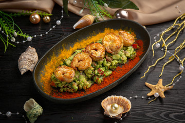 tartar shrimp with avocado and spices on a black oval plate