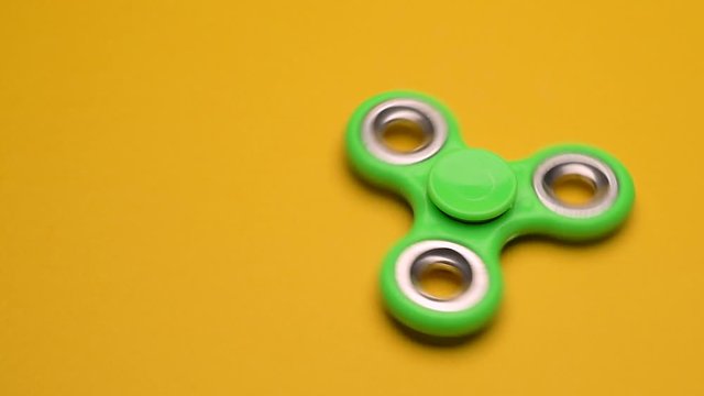 Green fidget spinner on yellow background