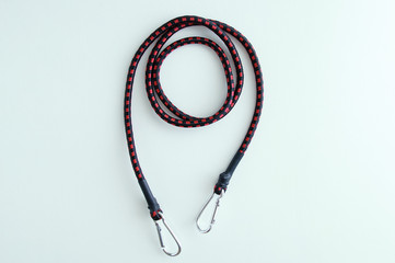 Rubber cord for securing luggage with metal carabiners on a white background.