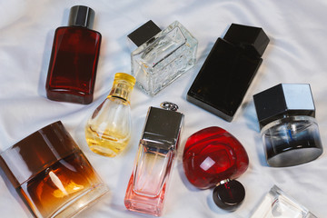 Colorful fashion trendy bottles of perfume toilet water fragrances  lie on a silver gray sheet on...