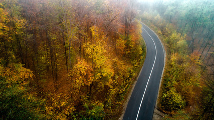 Aerial view of forest road in beautiful autumn. Mountain roads details with colourful landscape and yellow trees