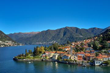 Fototapeta na wymiar Panoramic top view of Lake Como. Lombardy, Italy. The small town of Torno. Autumn season. Perfect clear blue sky. Boats parked off the coast