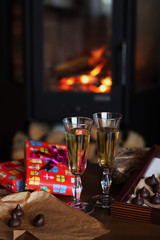 Glasses of drink are on the table by the fireplace