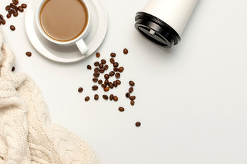 Coffee or tea paper cup, white cup with coffee, knitted plaid, coffee beans on light gray background top view flat lay copy space. Take away coffee cup, mockup. Minimal composition, layout for design