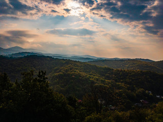 Beautiful mountains of the North Caucasus, covered with deciduous forest, painted with autumn colors in the sun, which shines through the clouds.