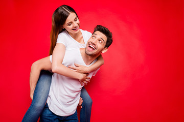 Photo of cheerful positive nice pretty couple of spouses with guy carrying piggyback girl and her riding his back hugging in jeans denim white t-shirt isolated vivid color background