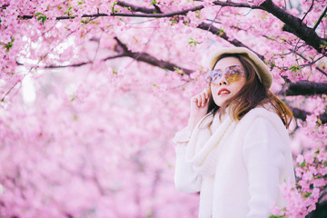 Happy travel woman and smile with sakura cherry blossoms tree on vacation while spring, asian